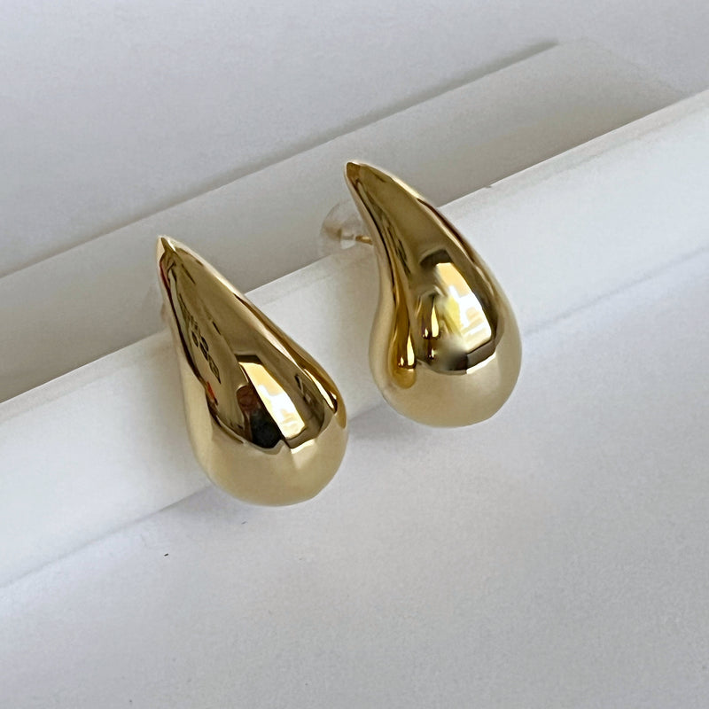 Un par de aretes de oro con una gota de oro en la parte inferior.